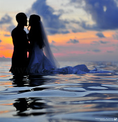 married-couple-embracing-wedding-day-in-water-clothes-on